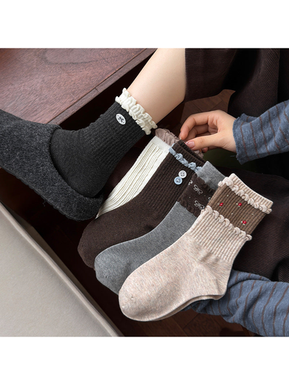 Multiple sock styles displayed together, with decorative cuffs, hearts, bows, buttons, and red embroidery.