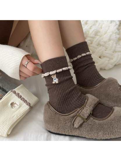 Coffee ribbed socks worn with buckle shoes, with a hand adjusting the cuff.