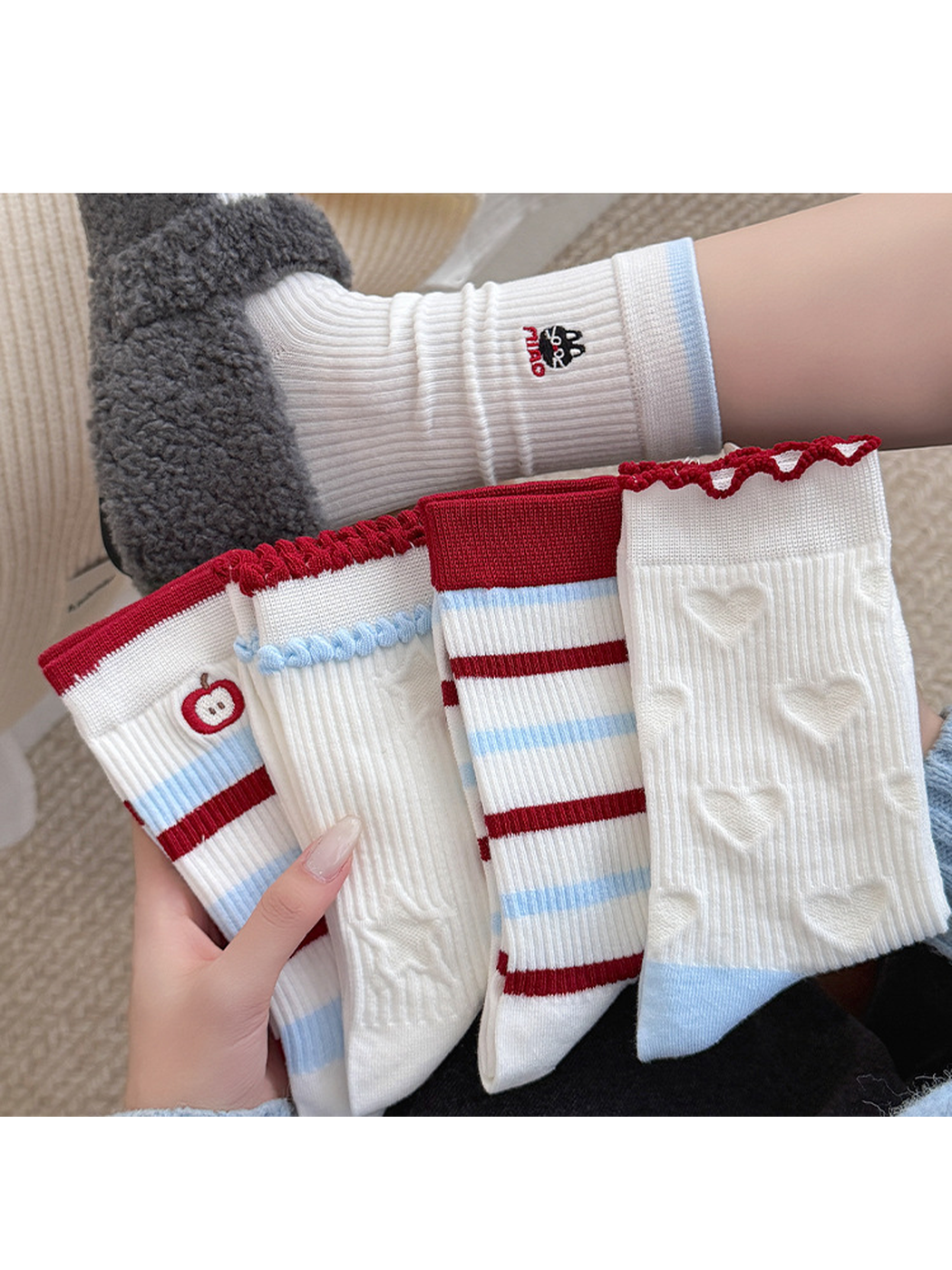Multiple Styles of white socks held together, with stripes, apple, heart and star designs beside a worn cat sock