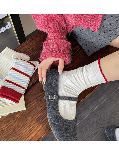 White heart-pattern socks with red cuff trim worn gathered above gray strap shoes, viewed from above