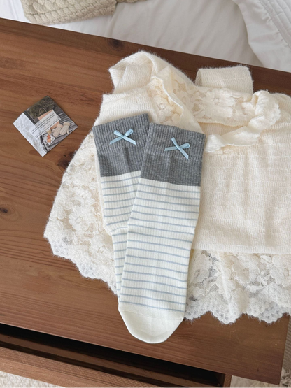 Bows socks with blue stripes, gray ribbed cuffs and pale blue bows, laid flat.