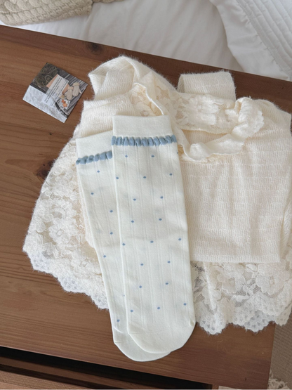 Dots socks with pale blue dots and ruffled trim, laid flat.
