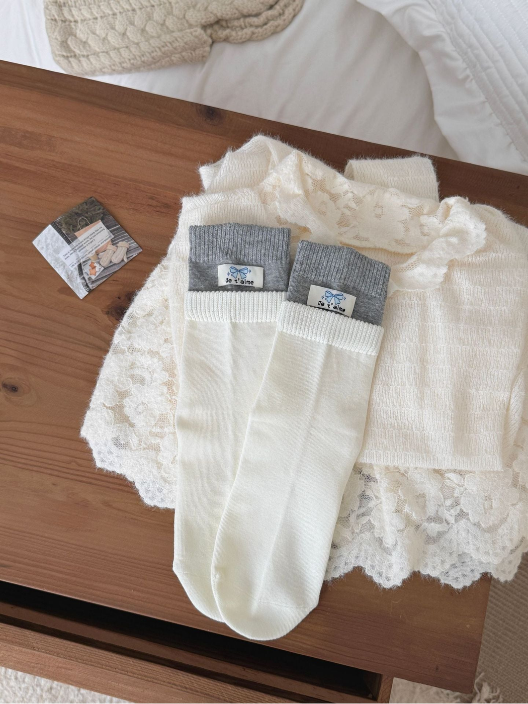Label socks with gray cuffs, white ribbed bands and bow labels, laid flat.