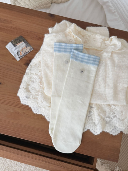 Plaid socks with pale blue checked cuffs and small heart-shaped accents, laid flat.