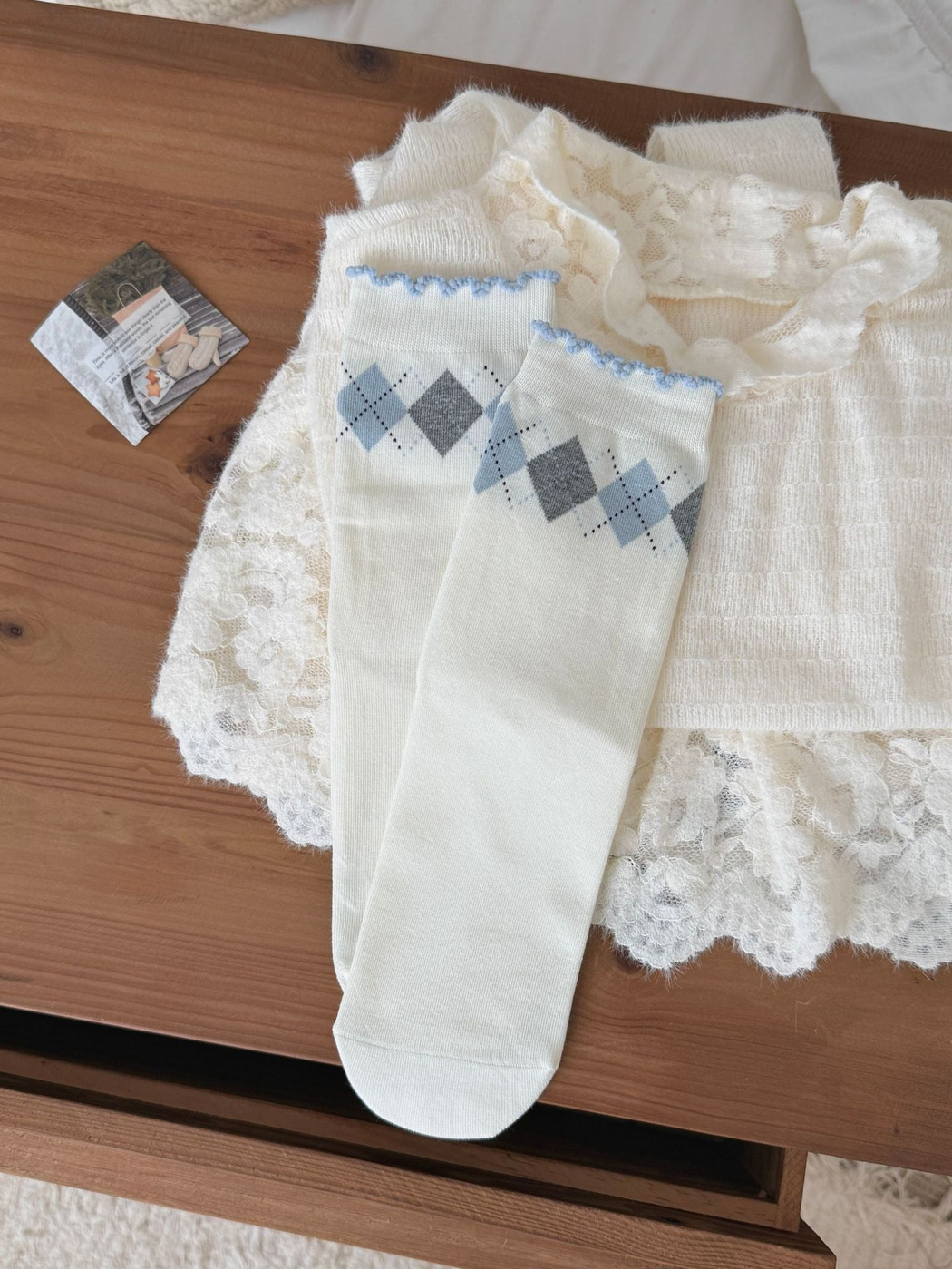 Argyle socks with blue and gray diamonds and scalloped blue cuff edges, laid flat.