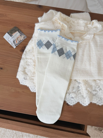 Argyle socks with blue and gray diamonds and scalloped blue cuff edges, laid flat.