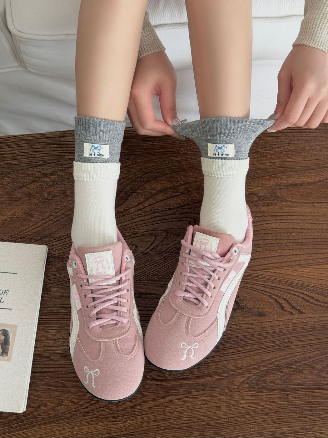 Hands pull outward on the gray cuff of Label socks worn with pink sneakers.