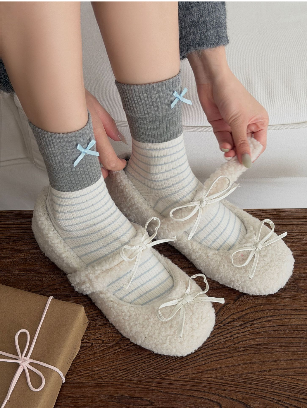 Bows socks worn with white textured flats while hands adjust the shoe straps.