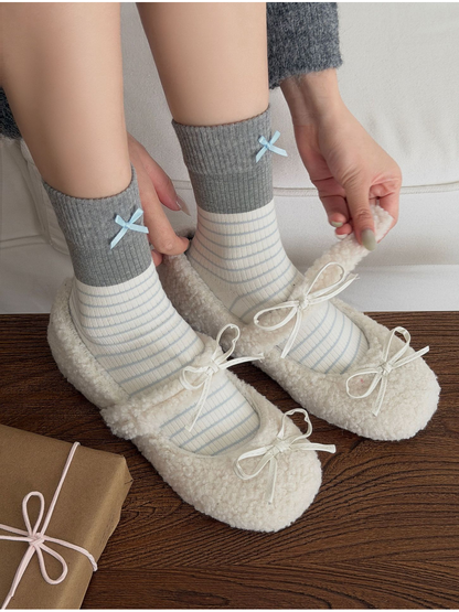 Bows socks worn with white textured flats while hands adjust the shoe straps.