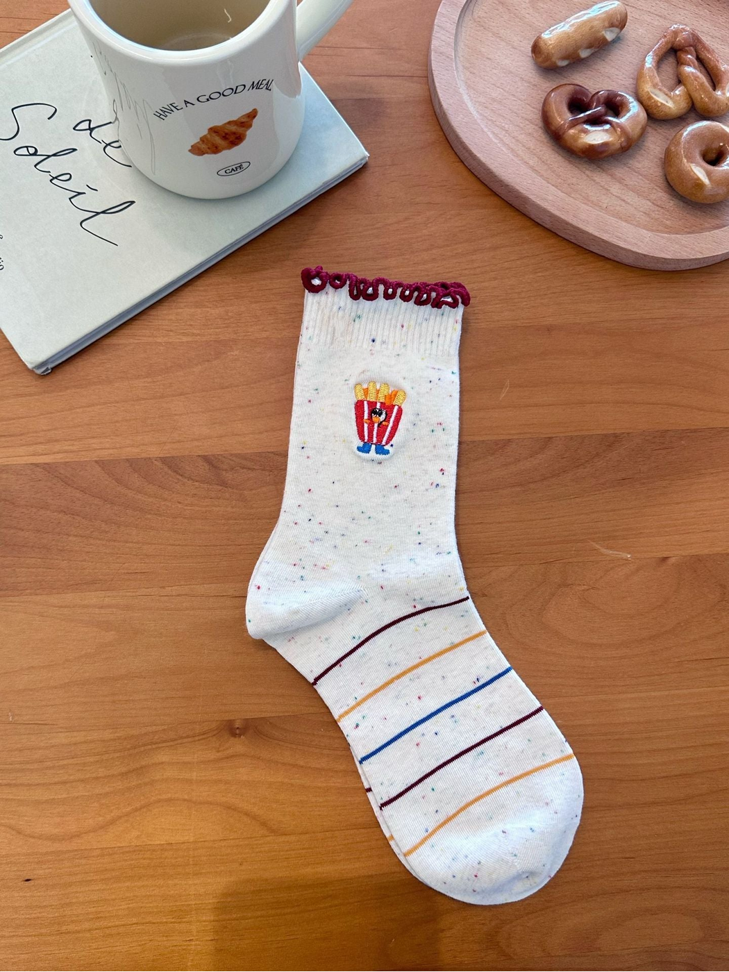 Fries style ivory speckled sock with burgundy looped cuff, fries embroidery, and striped foot, laid flat.