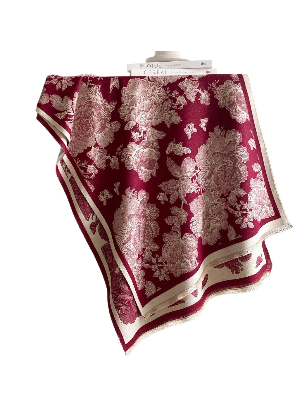 Burgundy scarf draped against a white background, with cream flowers, butterflies, contrasting borders, and short fringe.