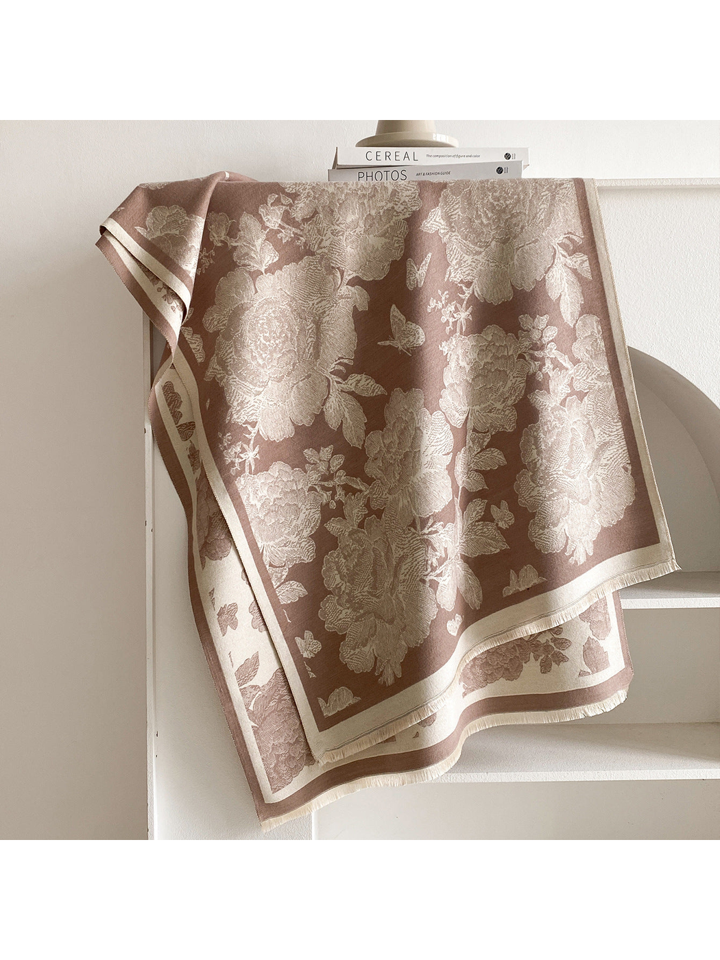 Coffee scarf draped to show cream floral and butterfly motifs, contrasting borders, and short fringe.