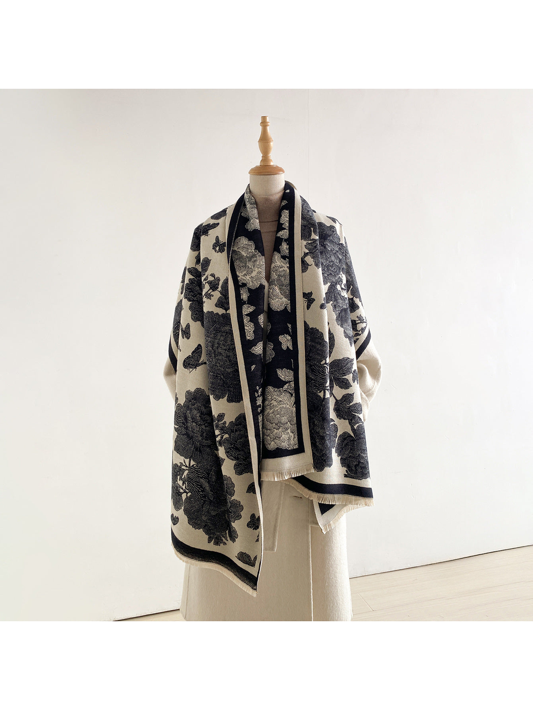 Black and cream floral scarf wrapped across a mannequin's shoulders with the cream side facing outward.