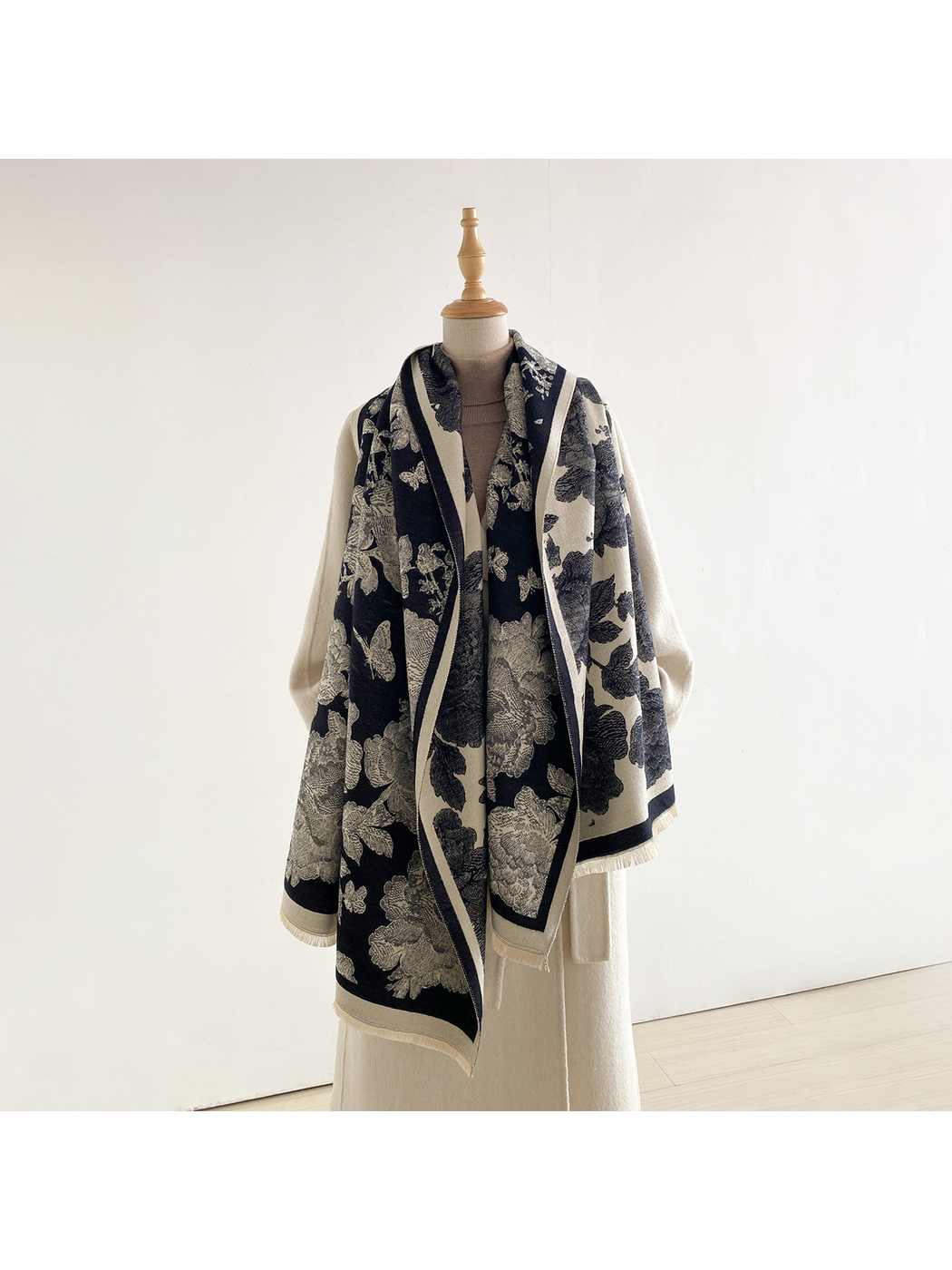 Black floral scarf draped loosely around a mannequin's neck, with long hanging ends and both contrasting sides visible.