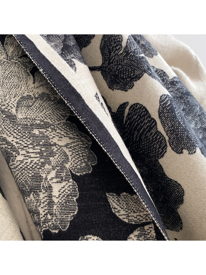 Close-up of the Black scarf's contrasting floral surfaces and stitched border.