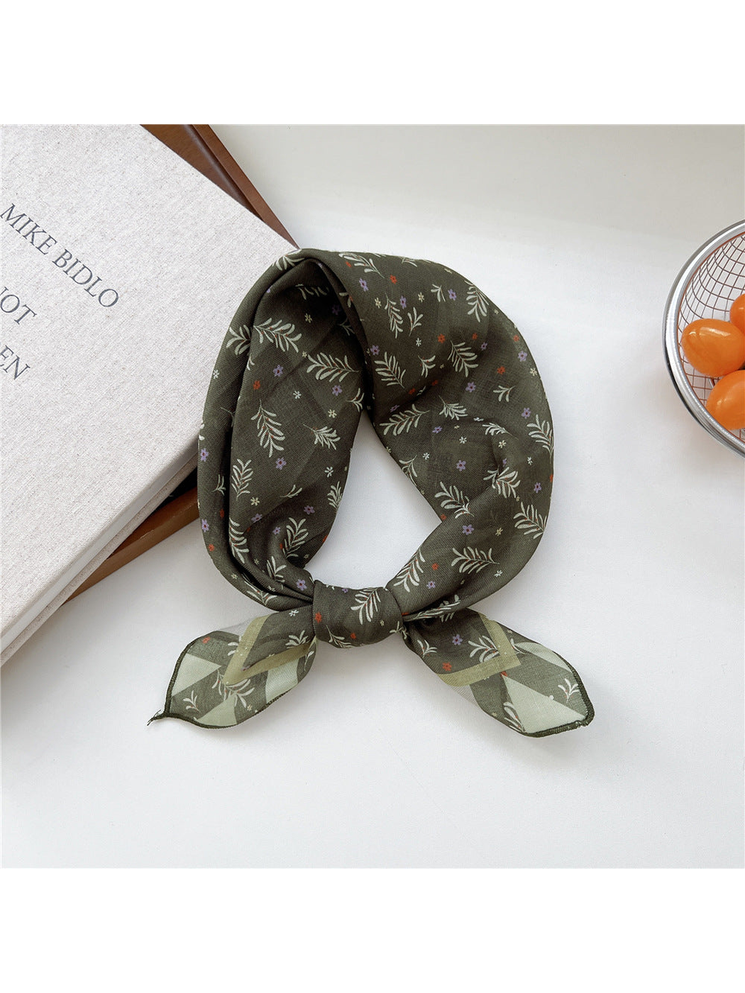 Green Sprigs scarf tied in a loop with small leafy sprigs and striped ends.