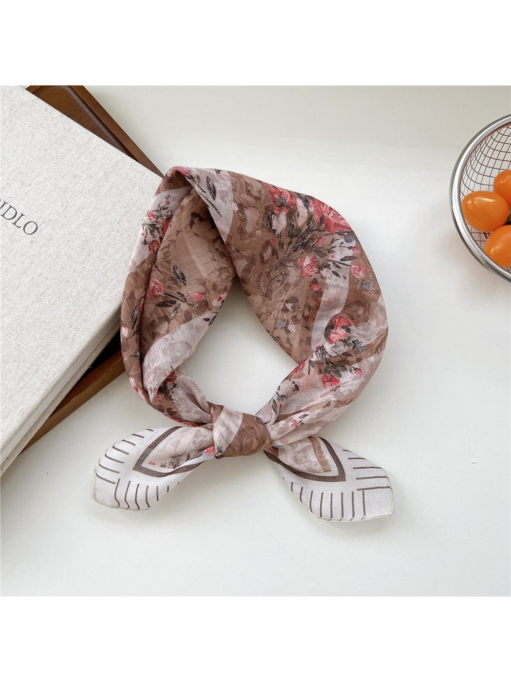 Coffee Floral scarf tied in a loop with pink bouquets and a fine lined border.