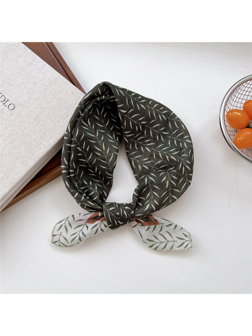 Green Bamboo scarf tied in a loop with slender pale leaves and contrasting ends.
