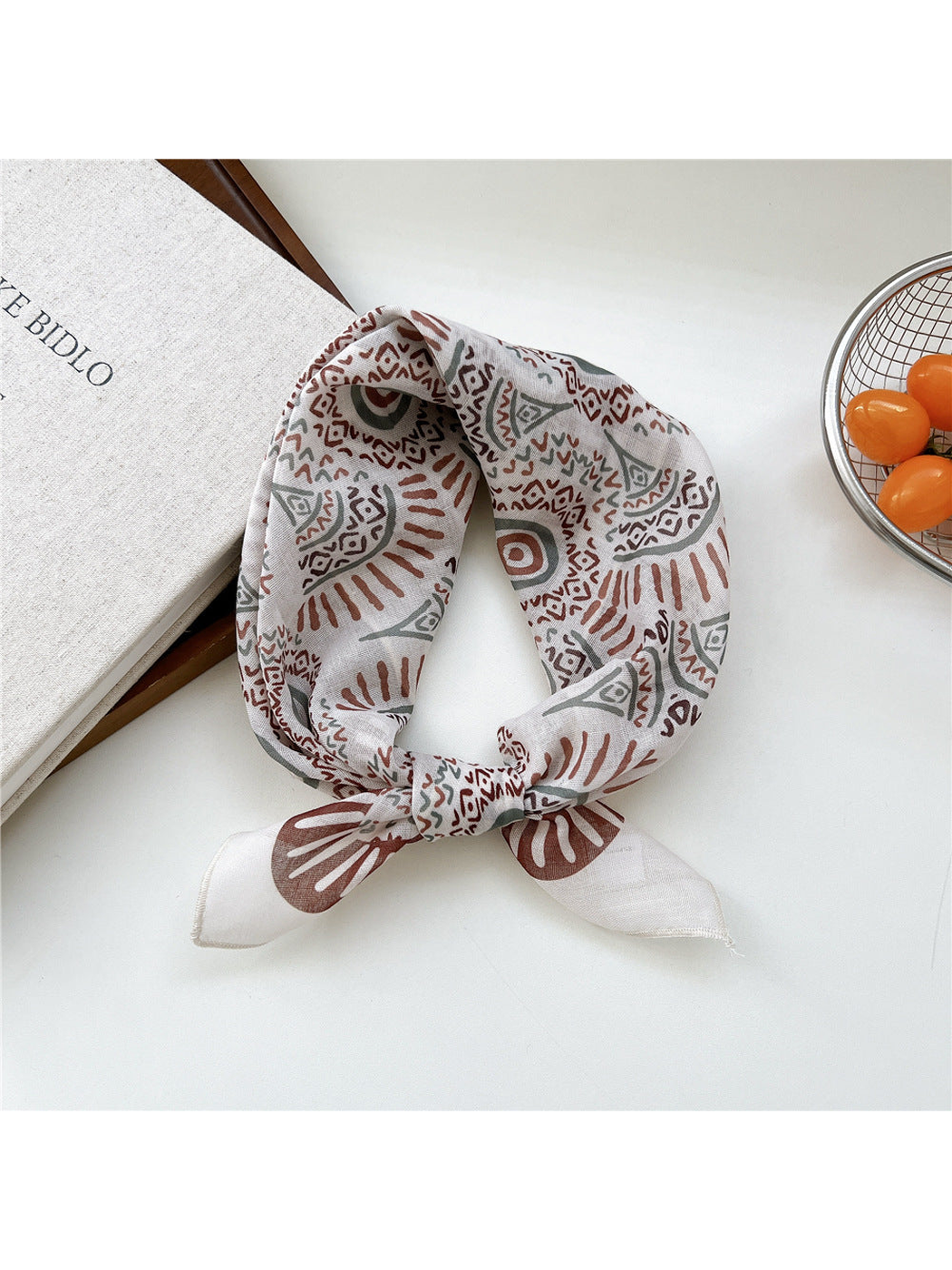 Ivory Sunburst scarf tied in a loop with brown and gray circular motifs.
