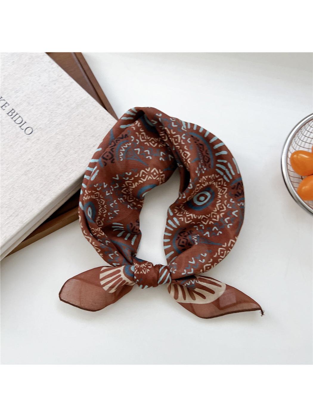 Caramel Sunburst scarf tied in a loop with blue and cream circular motifs.