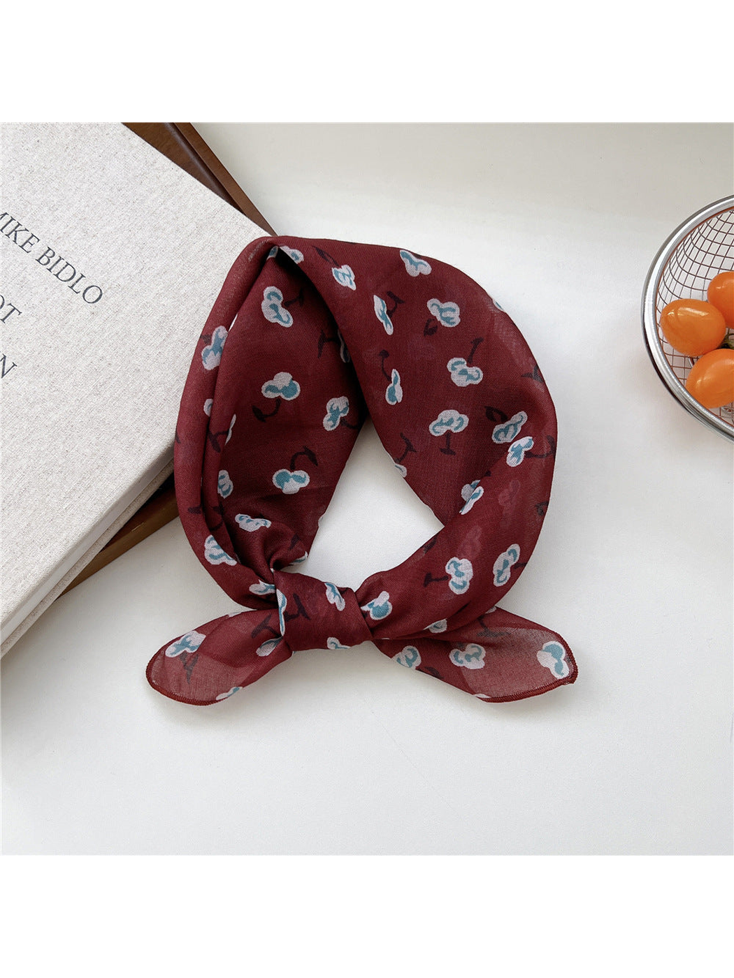 Burgundy Shapes scarf tied in a loop with scattered blue-and-white motifs.