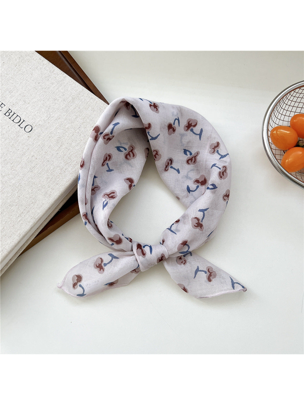 Ivory Shapes scarf tied in a loop with scattered brown-and-blue motifs.