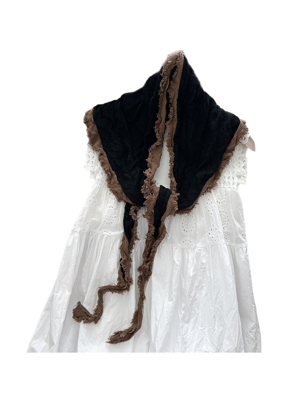 Black scarf with brown frayed trim, draped and knotted over a white dress.