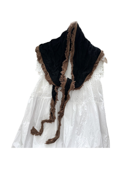 Black scarf with brown frayed trim, draped and knotted over a white dress.