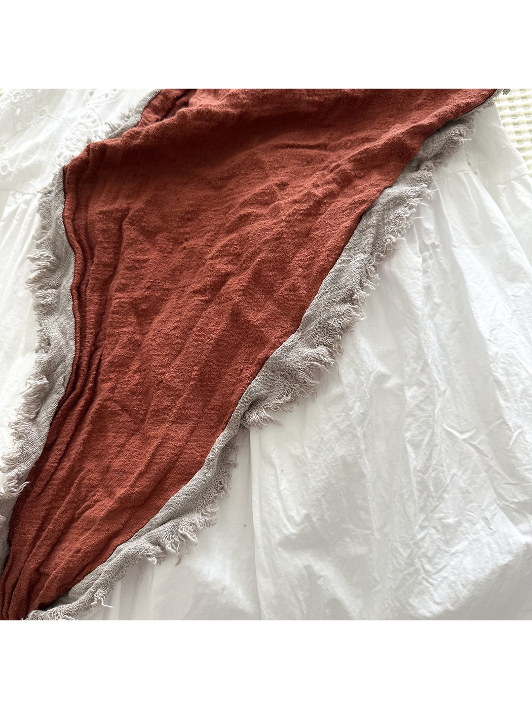 Close-up of the Orange Red scarf's crinkled surface and contrasting gray fringed edge.