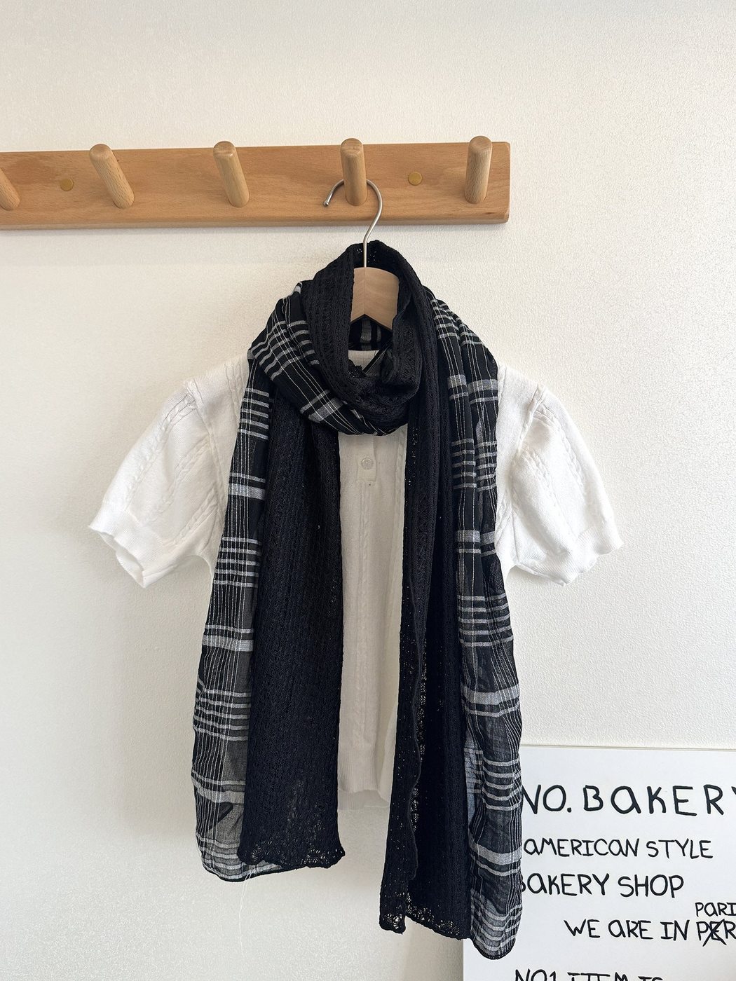 Black Gray plaid scarf with black openwork panels looped over a white top on a hanger.