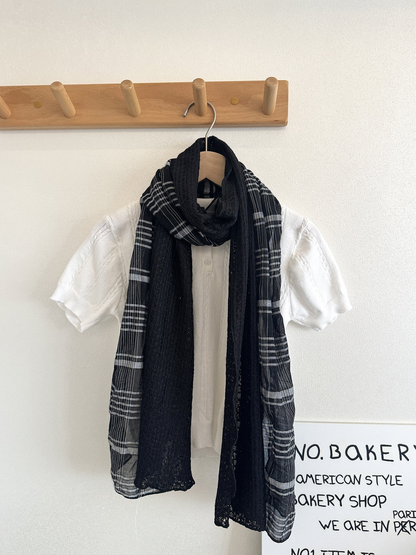 Black Gray plaid scarf with black openwork panels looped over a white top on a hanger.