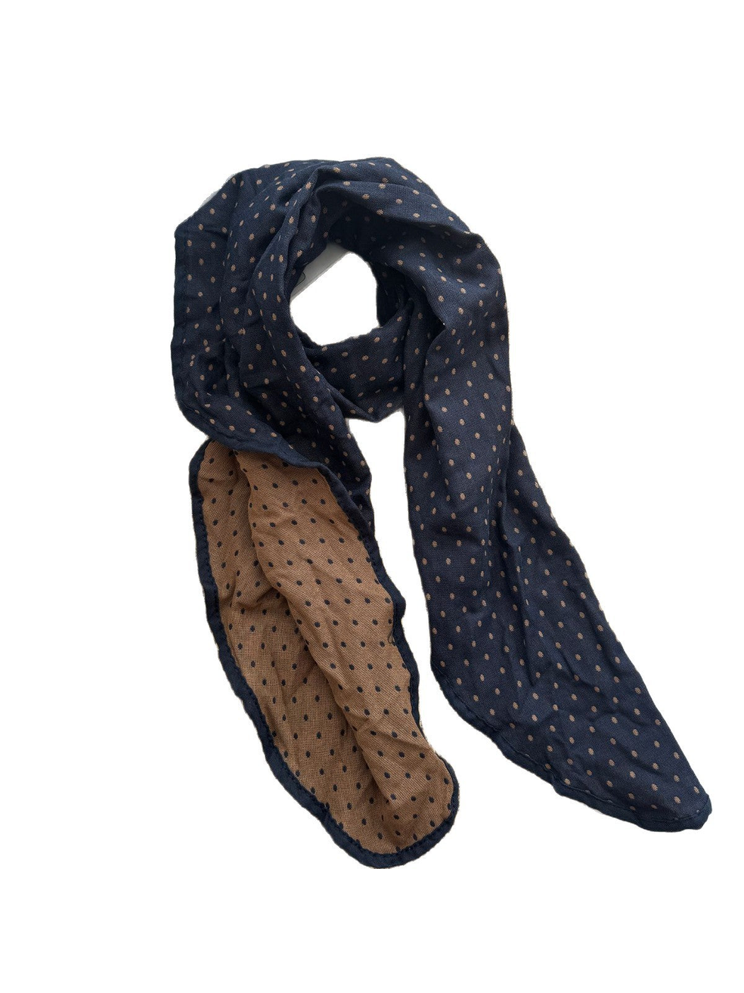 Navy polka dot scarf arranged in a loop with its tan reverse and rounded ends visible.