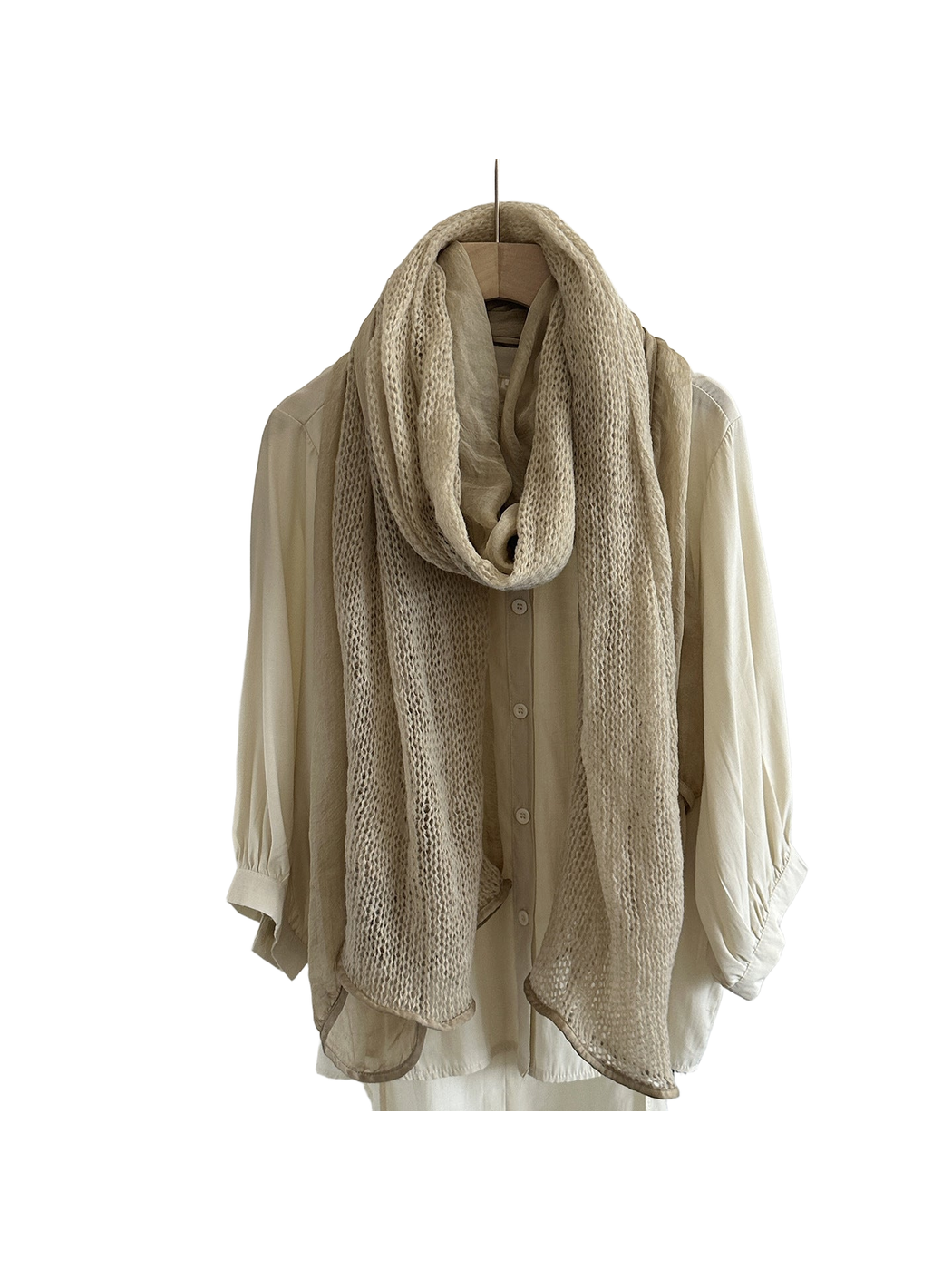 Beige scarf with openwork and sheer panels hanging in a long loop over a cream shirt.