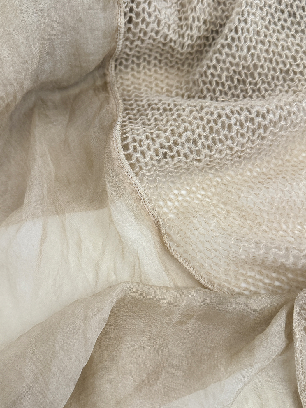 Close-up of the scarf's openwork panel, sheer panel and stitched joining edge.