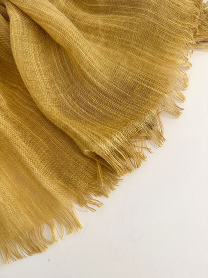 Close-up of the Mustard Yellow scarf's open weave and fine fringe against a pale background.