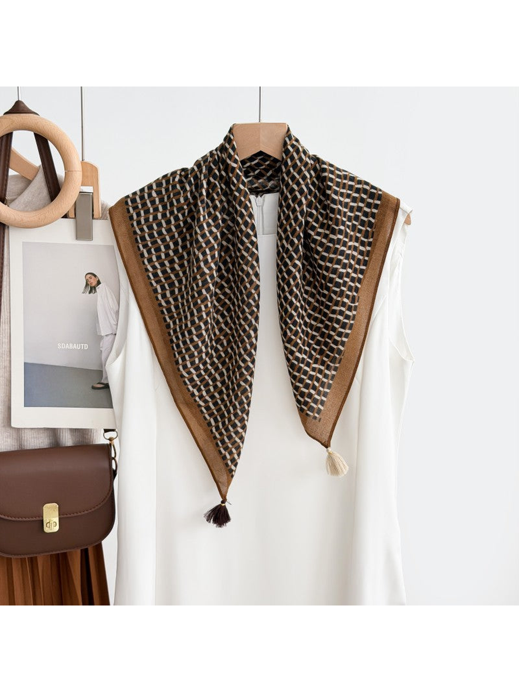 Brown geometric grid scarf with contrasting corner tassels draped over a white sleeveless top.