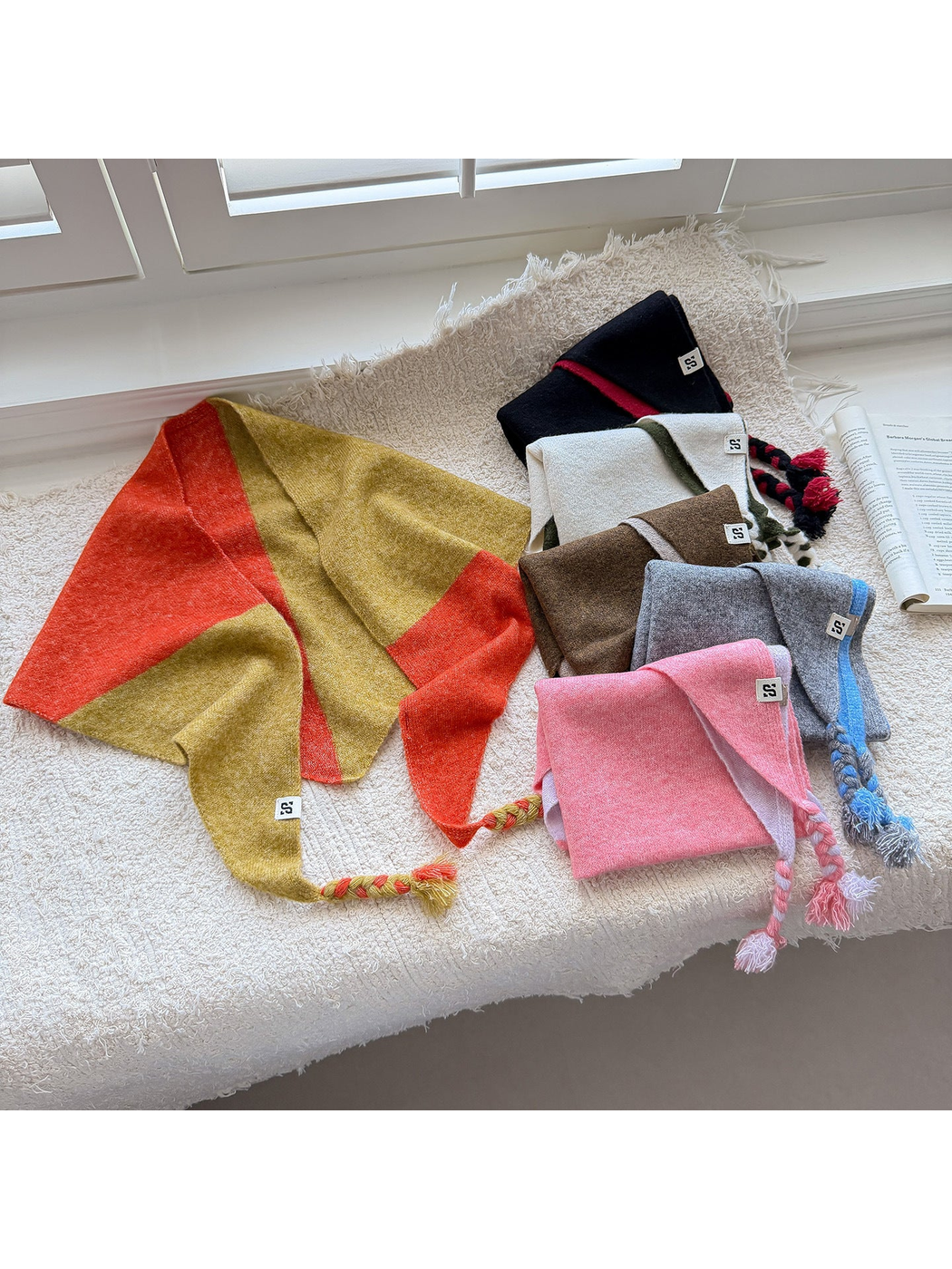 Six color block triangle scarves arranged together with braided tassel ends