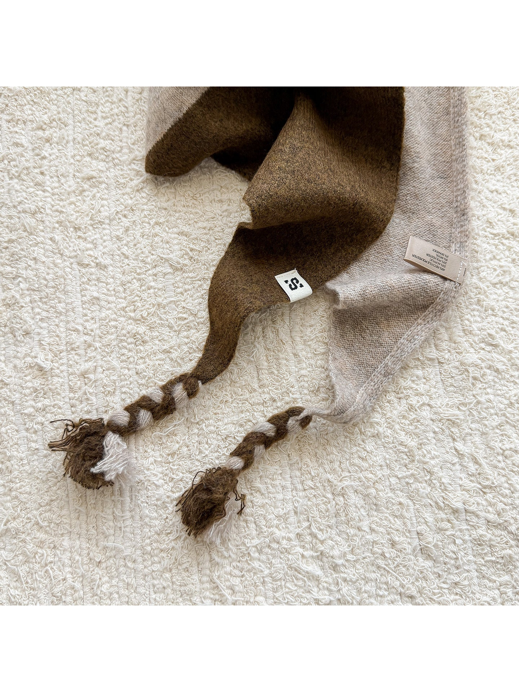 Close-up of the Coffee scarf's knit texture and two-tone braided tassels