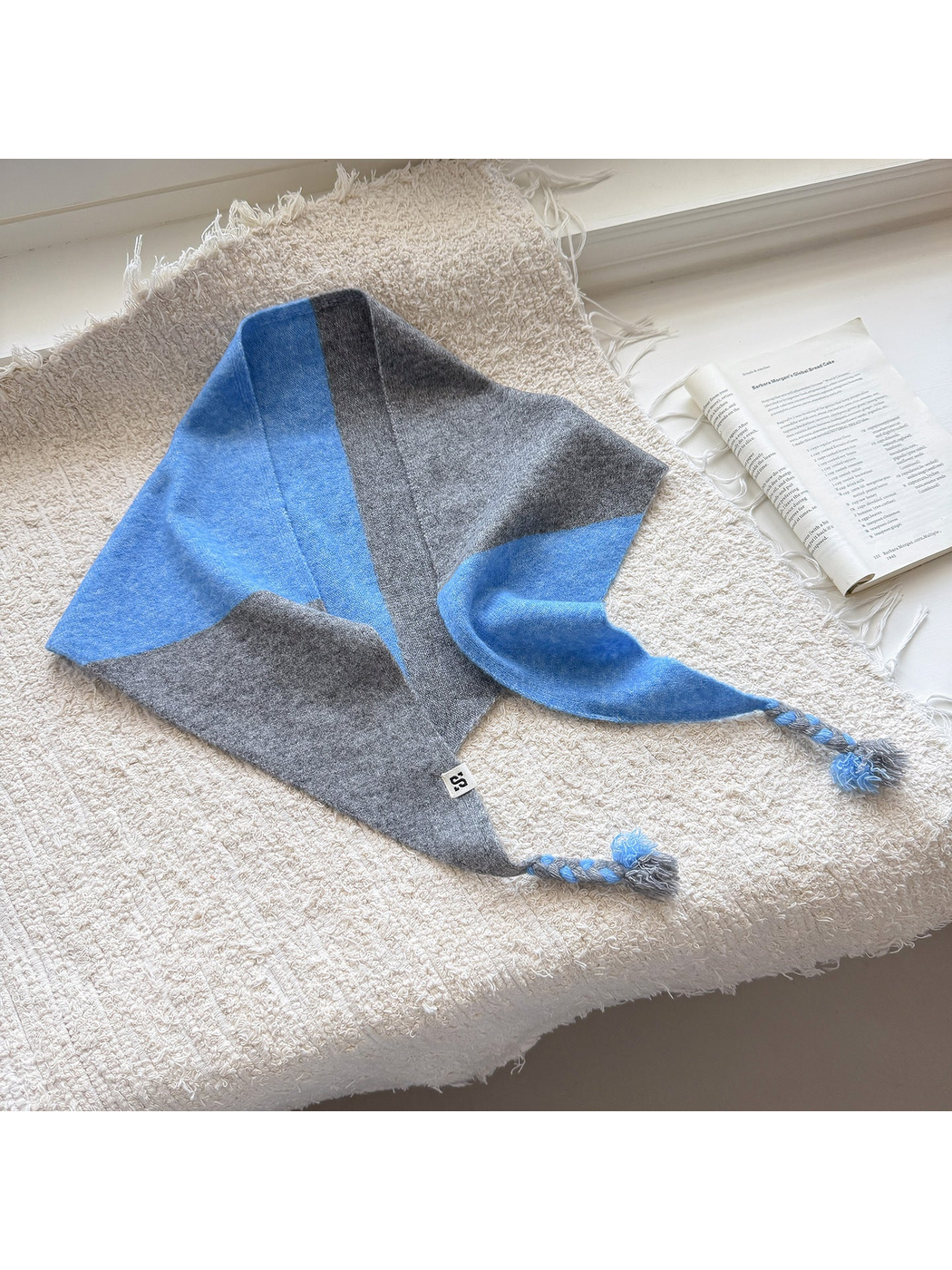 Gray Blue color block triangle scarf with braided tassel ends spread across a textured surface
