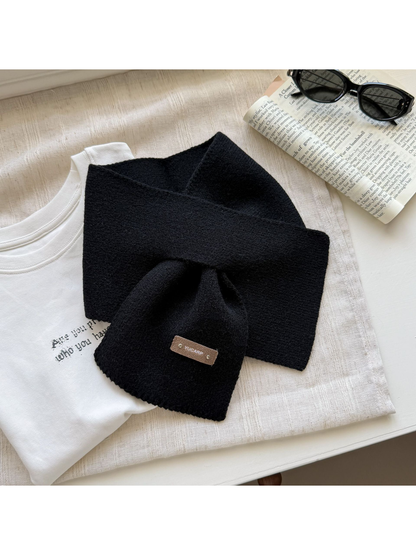 Black knit pull-through scarf with a rectangular label near one end.