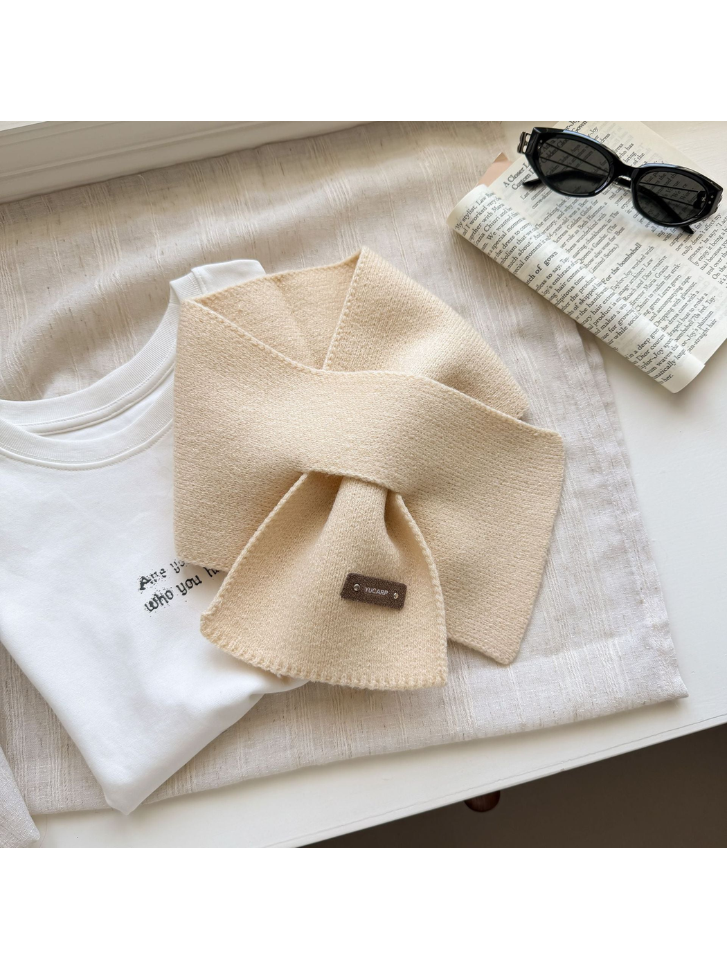 Beige knit pull-through scarf arranged with crossed ends.