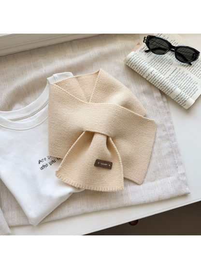 Beige knit pull-through scarf arranged with crossed ends.