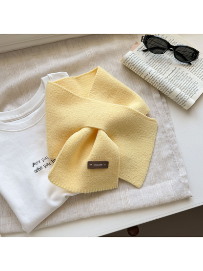 Yellow knit pull-through scarf arranged with crossed ends.