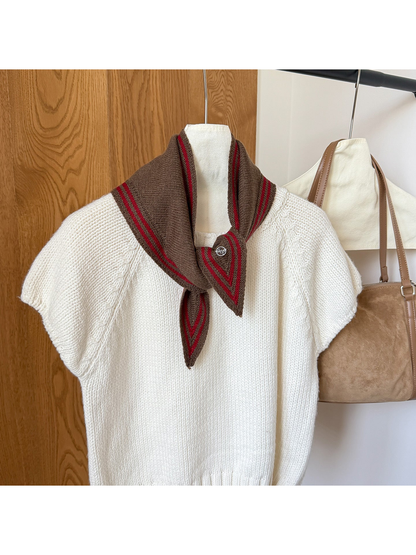 Brown knit triangle scarf with red border stripes tied around the neckline of a white top.