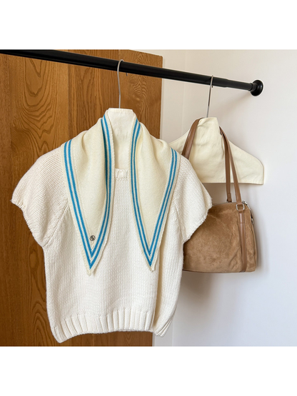 Ivory knit triangle scarf with blue border stripes draped over a white top.