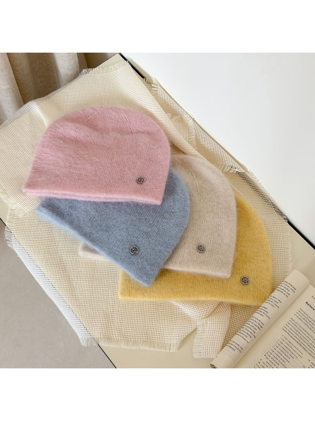 Light Pink, Light Blue, Ivory and Yellow beanies layered together with round silver-tone emblems.