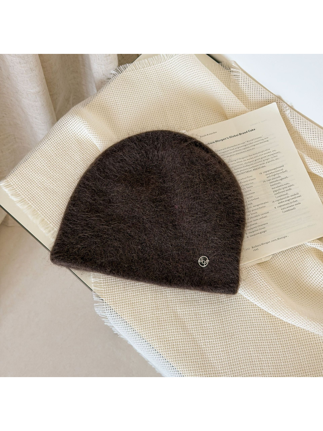 Dark Brown fuzzy knit beanie with a rounded crown and small silver-tone emblem.