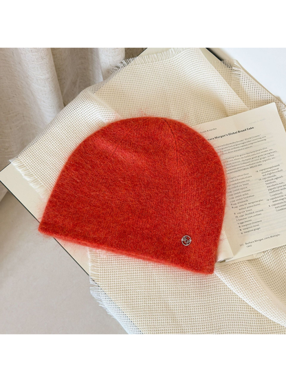 Orange Red fuzzy knit beanie with a rounded crown and small silver-tone emblem.