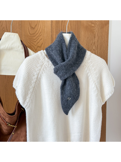 Dark Gray fuzzy knit scarf looped over a white knit top, with a tapered end and round silver-tone emblem.