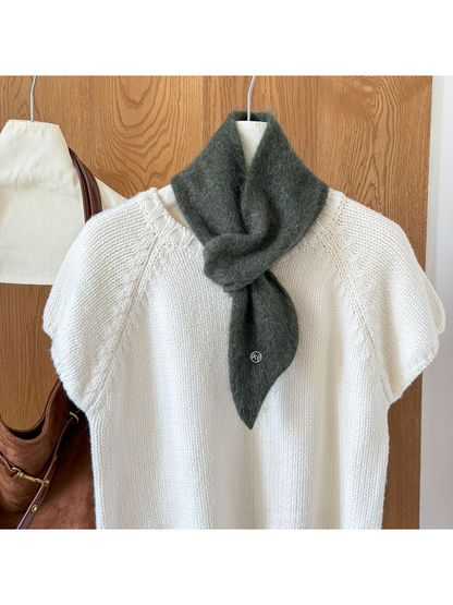 Army Green fuzzy knit scarf looped over a white knit top, with a tapered end and round silver-tone emblem.
